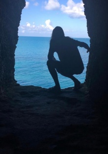 Alexa in a cave opening overlooking the ocean. 