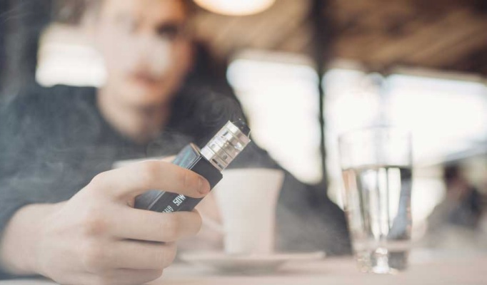 Closeup image of an e-cigarette in a cloud of smoke. 