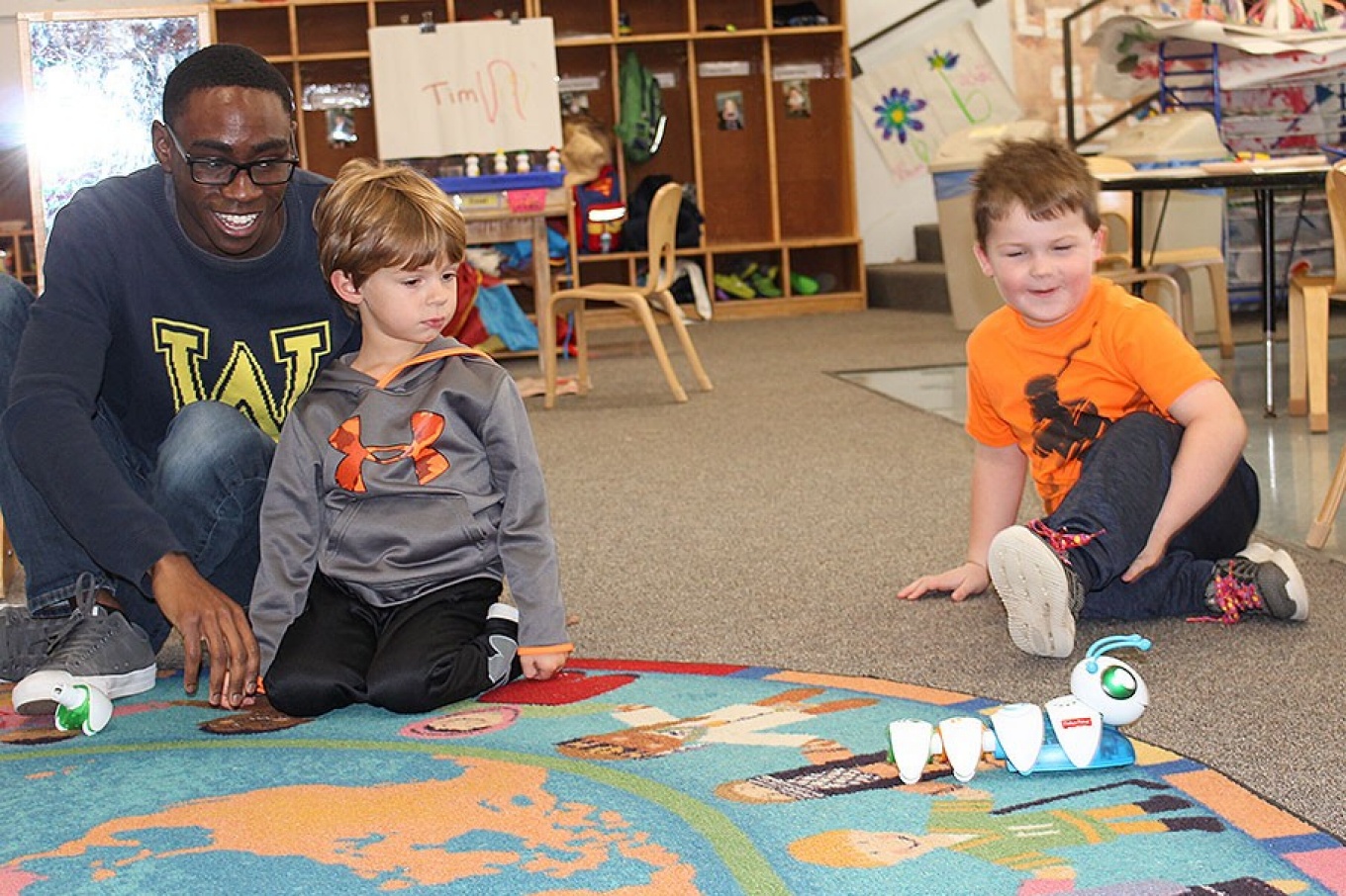 Teacher Stanley Diih and children Griffin Maines and Lochlan Schlader play with the code-a-pillar.