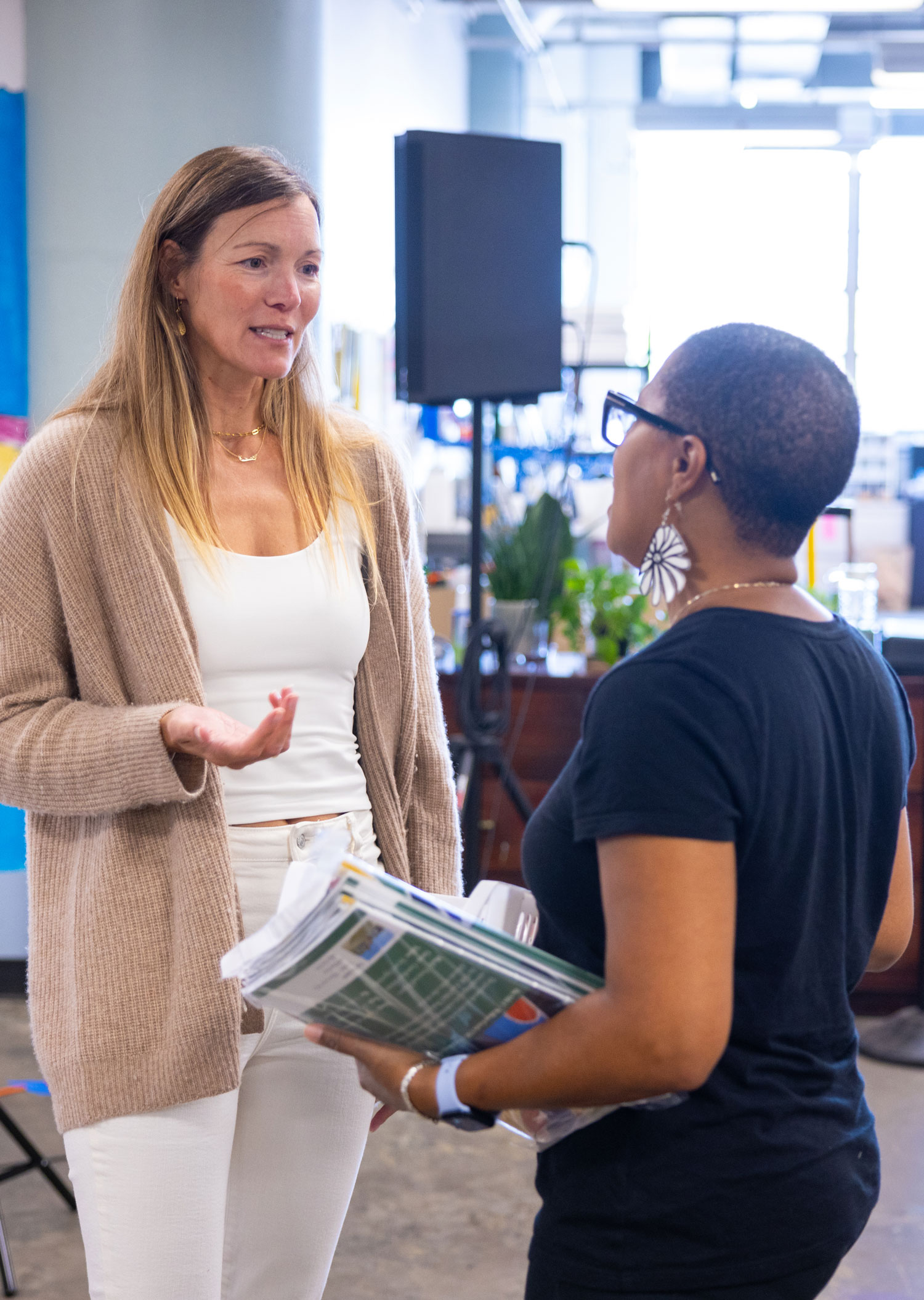 Teacher standing next to student desks in classroom.