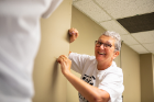 Gerri Kremer removes tape from a wall before it is painted.