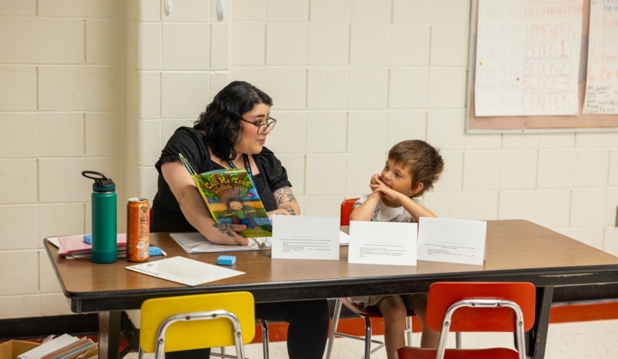 A teacher reading a book to a student. 