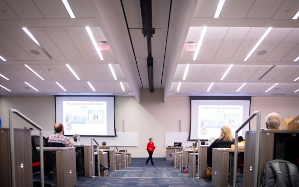 Faculty giving lecture in large lecture hall. 