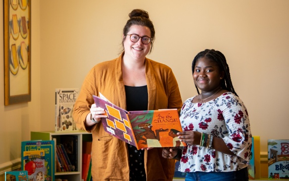 Mirna Cadet is photographed in the reading area she and fellow members of Team Traffic Cones created in the women and children's shelter in the Buffalo City Mission in June 2023. The group collected more than 1,000 books which were donated to the women’s and men’s shelters. With her is April Parkhill, adult education coordinator for Buffalo City Mission at Cornerstone Manor, the women and children’s shelter. Photographer: Meredith Forrest Kulwicki. 