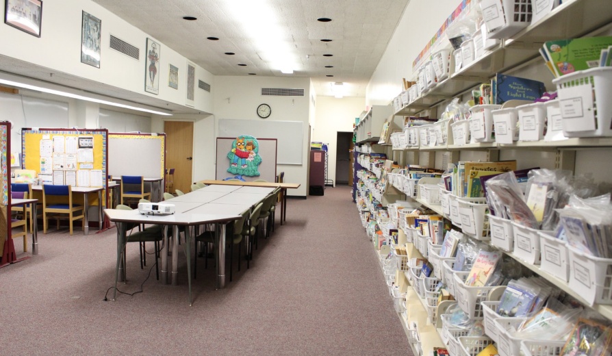 A wall full of books and a few tables for tutoring. 