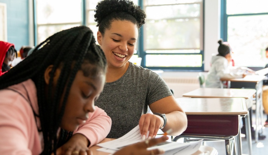 Student teacher helps child with reading in a classroom. 