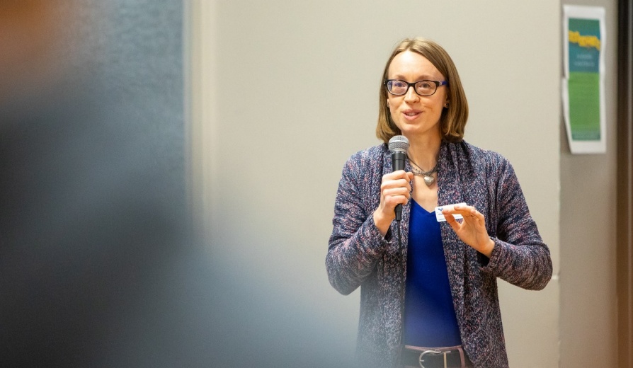 Faculty member holds microphone while giving a speech. 