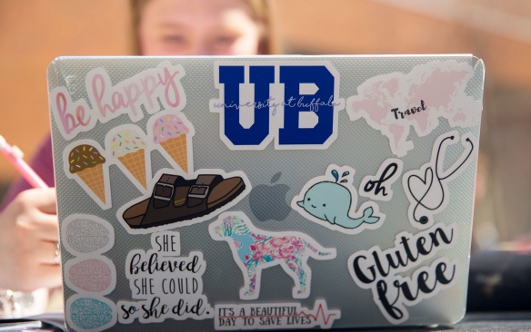 A student studies at a laptop covered in stickers.,. 