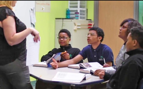 A teacher stands in front of a classroom engaged in a lesson. 