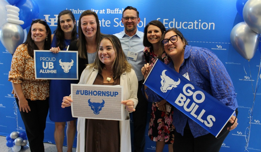 LiFTS alumni pose with UB Bulls branded signs. 