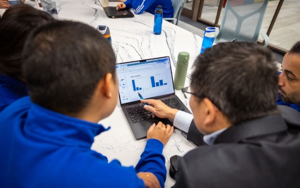 Students and faculty reviewing data on a laptop. 