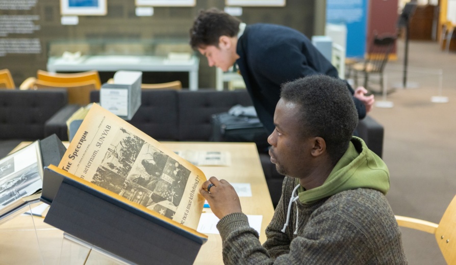 Students in Crystal Campbell’s media study class visit the Libraries Poetry Collection in Capen Hall in March 2024. Materials they interacted with included The Spectrum newspapers, university flags and banners, as well as other things. Photographer: Douglas Levere. 