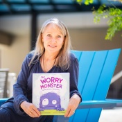 A portrait of Catherine Cook-Cottone, a professor of counseling, in the School and Educational Psychology, in the Graduate School of Education, taken in June 2024 in Paula’s Plaza on North Campus. She is photographed with her new book, “The Worry Monster.” Photographer: Meredith Forrest Kulwicki. 