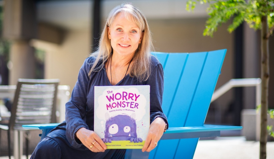 A portrait of Catherine Cook-Cottone, a professor of counseling, in the School and Educational Psychology, in the Graduate School of Education, taken in June 2024 in Paula’s Plaza on North Campus. She is photographed with her new book, “The Worry Monster.” Photographer: Meredith Forrest Kulwicki. 