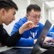 Two students working on laptops in the Center for the Arts. 