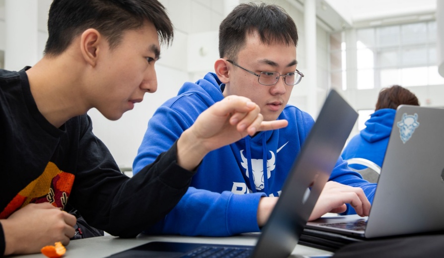 Two students working on laptops in the Center for the Arts. 