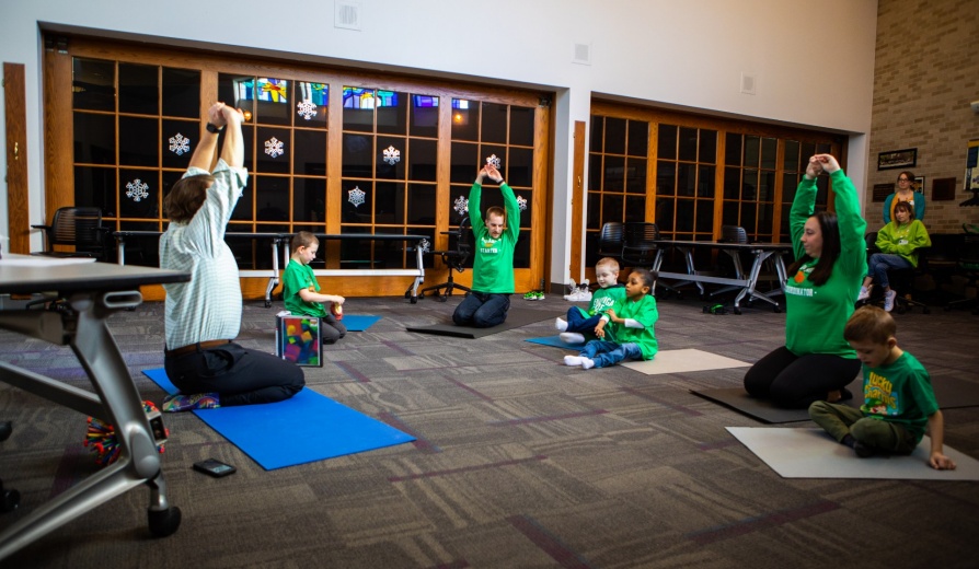 Catherine Cook-Cottone, professor of counseling, school and educational psychology, and Claire Cameron, associate professor of learning and instruction, study how yoga and mindfulness-based programs for children help establish body awareness, decrease anxiety and assist stress management. Vito Gigante, director of occupational therapy at the Beyond Learning Center (formerly the Cantalician Center for Learning) leads young children in a yoga practice. Photographer: Douglas Levere. 