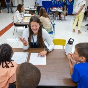 Young students at a desk with a teacher. 