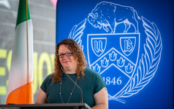 Woman standing in front of a podium with the UB seal as s backdrop. 