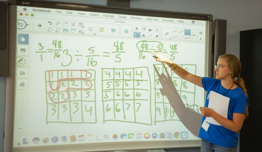 Student giving a math lesson to a class on a projection board. 