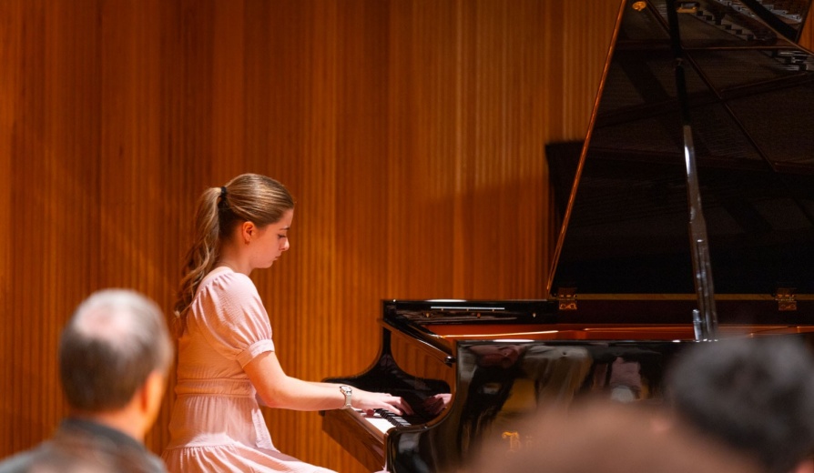 Student giving a piano performance on stage in Slee Hall. 