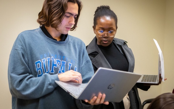 Two students meeting holding laptops. 