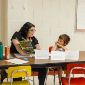 A teacher reading a book to a student. 