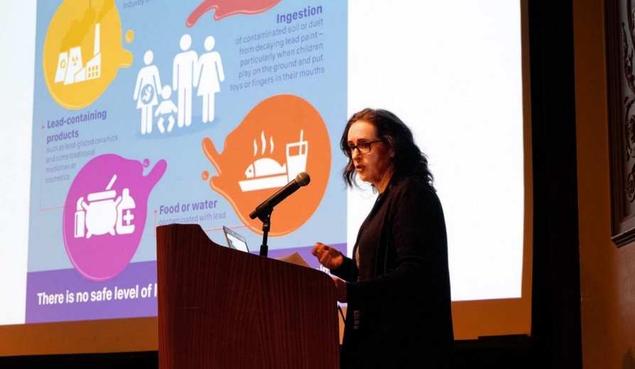 Leah Bartlo speaks at podium with presentation slide in the background. 