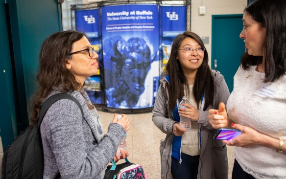 Female students meeting with a professor in a hallway. 