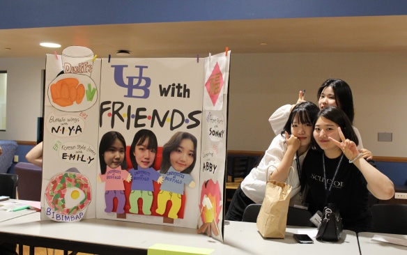 Three Korean students pose next to their poster. 