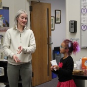 A tutor at the front of a classroom with her student as they read. 