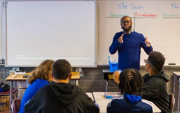 Male teacher delivering a lesson in a middle school classroom. 