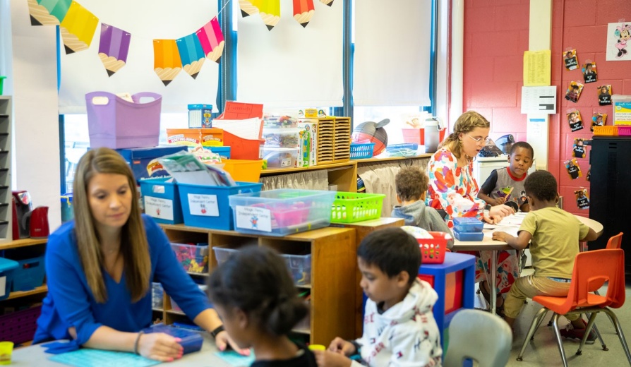 Two teachers in an elementary classroom engaged in lessons with students. 