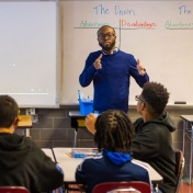 Male teacher delivering a lesson in a middle school classroom. 