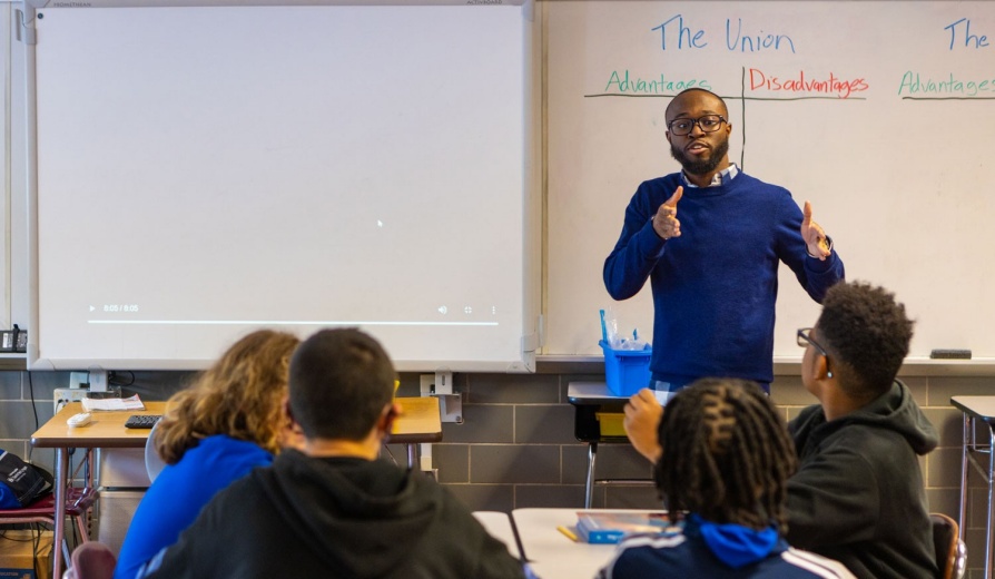 Male teacher delivering a lesson in a middle school classroom. 