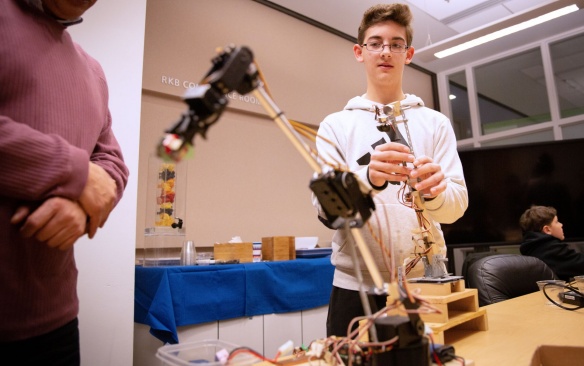 Student manipulating a robot with oversight of teacher. 