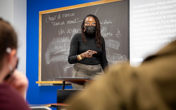 Teacher with students in a classroom teaching french lesson on blackboard. 