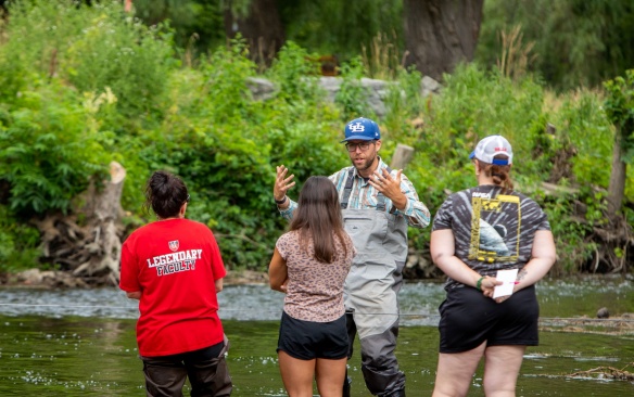 Teacher with students in a creek giving an environmental lesson. 