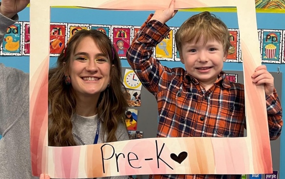 Tesacher with a pre-k student in a paper frame. 