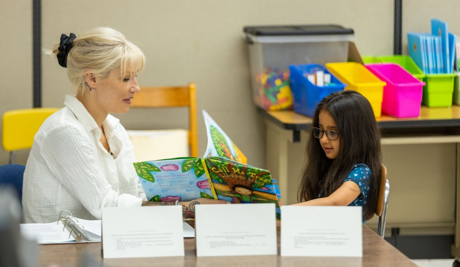 Teacher working with a student learning how to read. 