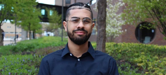 Portait phot of UB Teach student Russel Bassarath taken outside with trees and green bushes in background. 