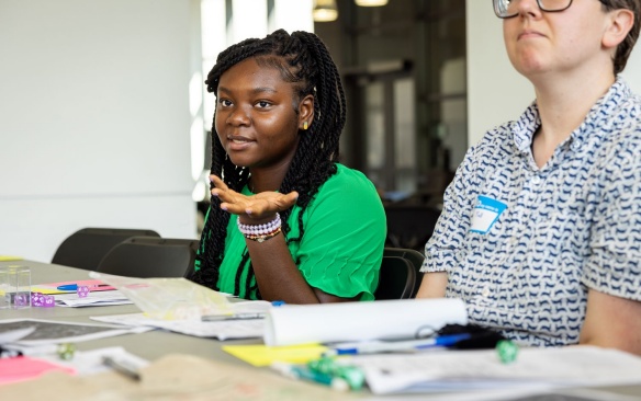 Student working at a desk covered in paperwork.