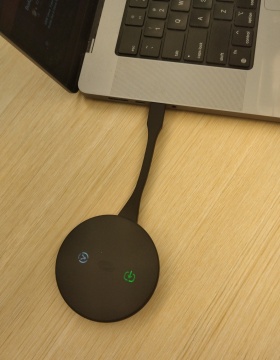 Zoom image: Puck adapter is connected to a USB-C port on laptop. 