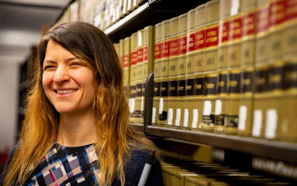 A portrait of law student Maura Kutnyak-Smalley in the Charles B. Sears Law Library, in O’Brian Hall, photographed in May 2022. Photographer: Meredith Forrest Kulwicki. 