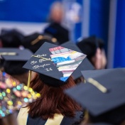 A grad cap decorated with a painted stack of books reading "On to the next chapter '26.". 