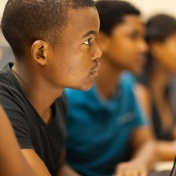 Nathan J. Daun-Barnett with students working on FAFSA project around computer. 