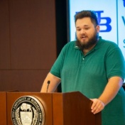 Justin Downey speaking at a podium. 