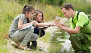 Faculty member collecting water samples with students. 