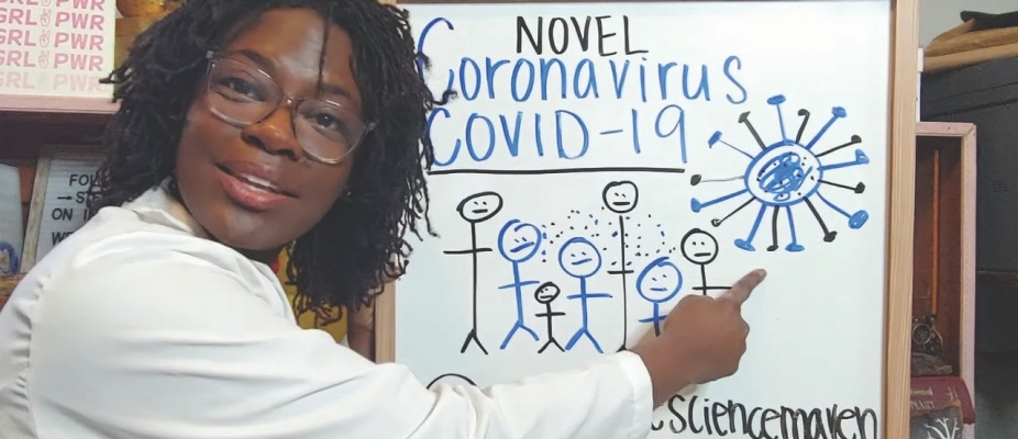 A still from Raven Baxter's Wipe It Down video on YouTube, with Baxter in front of a whiteboard (depicted, Novel Coronavirus COVID-19 and sketches). 