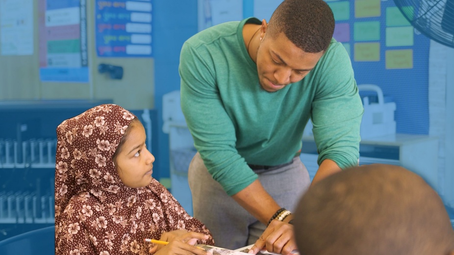 Cover story photo: A teacher helping a student in classroom. 
